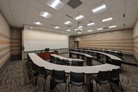 Front of room view with lectern on in front of markerboard, with exit door on the right