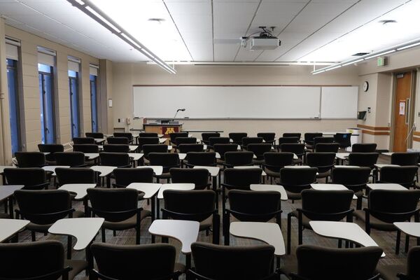 Front of room view with lectern on left in front of markerboard and exit door on right wall