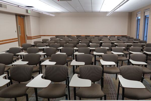 Back of room view of student tablet arm seating and exit door at left wall near rear of room