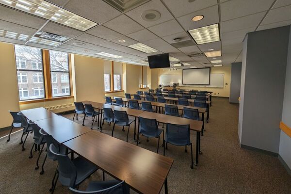 Front of room view with lectern on left in front of markerboard and projection screen partially lowered