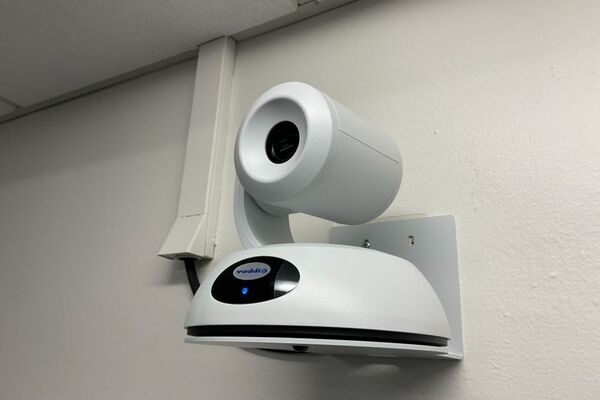 Camera mounted to a wall and instructor enabled adjustments to the lens to allow the instructor to be "seen" by the camera in more locations around the room