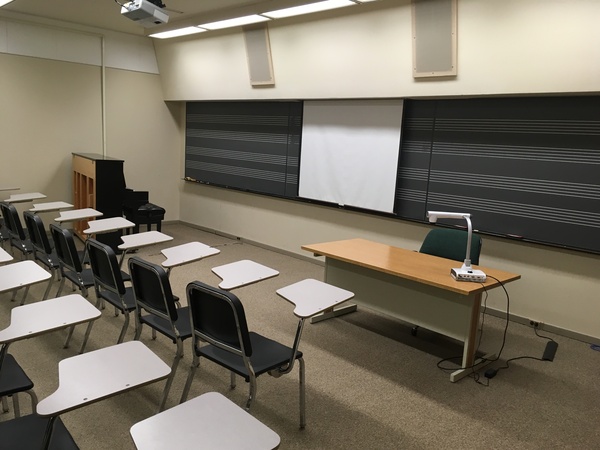 Photo of front of room from back of room with music staff chalkboard and piano.