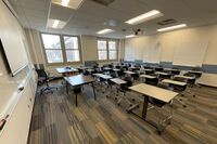 Back of room view of student tablet arm seating, markerboards, and camera on rear wall of room