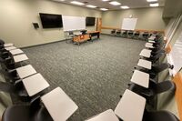 Front of room view with lectern in front of markerboard and display monitors to the left and right