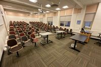 Back of room view of student auditorium seating and and exit door at left side of room