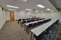 Front of room view with lectern on right in front of markerboard, door on left side