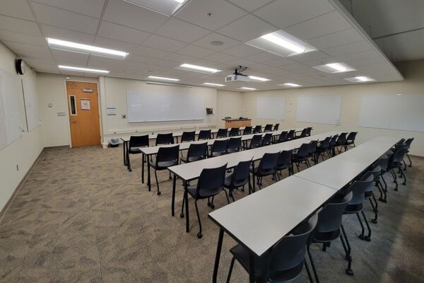 Front of room view with lectern on right in front of markerboard, door on left side