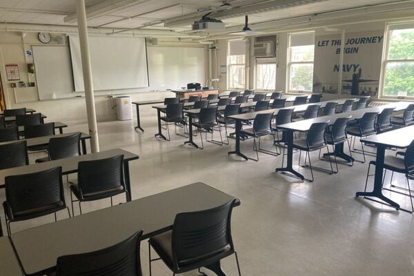 Front of room view with lectern on right in front of markerboard, screen lowered over middle of markerboard 