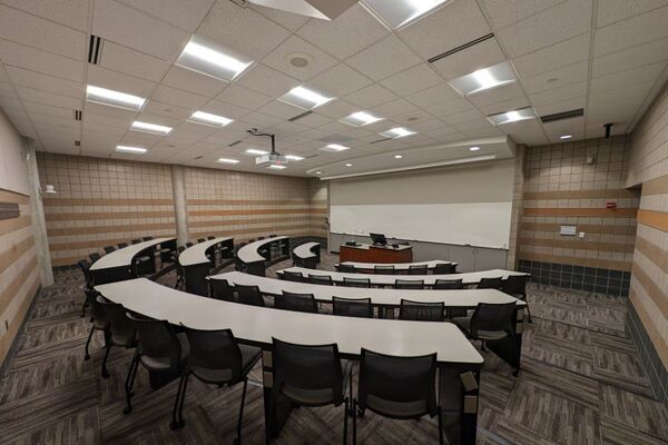 Front of room view with lectern center in front of markerboard with exit door at front right