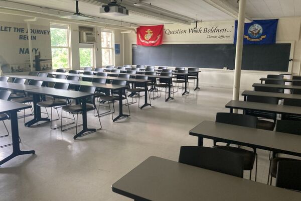 Back of room view of student table and chair seating and chalkboard on rear wall of room