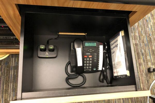 Pedestal - inside view of drawer showing two wireless mics in charging base and telephone