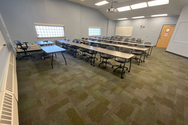 Back of room view of student table and chair seating and exit door at right rear of room