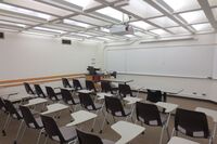 Front of room view with lectern on left side and projection screen fully raised