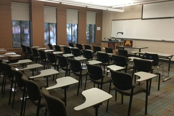 Front of room view with lectern on left in front of markerboard and projection screen partially lowered