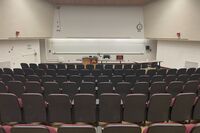 Front of room view with lectern on left in front of markerboard and projection above