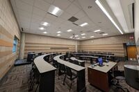 Back of room view of student tiered fixed-table and chair seating 