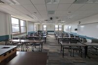 Back of room view of student table and chair seating and markerboards on right side wall