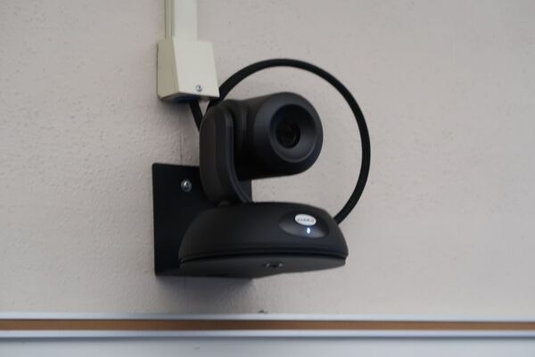 Camera mounted to a wall and instructor enabled adjustments to the lens to allow the instructor to be "seen" by the camera in more locations around the room