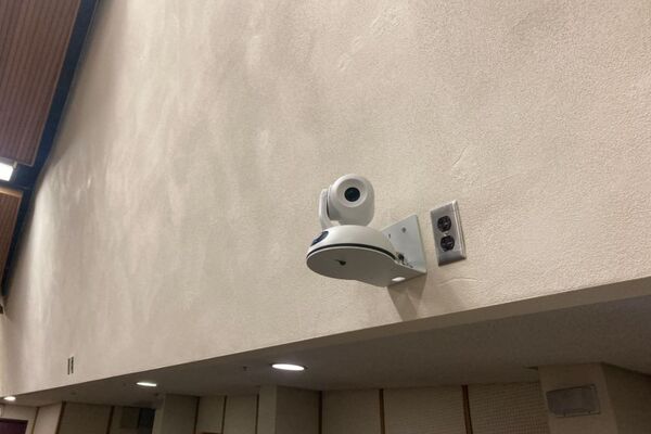 Camera mounted to a wall and instructor enabled adjustments to the lens to allow the instructor to be "seen" by the camera in more locations around the room