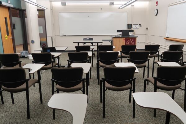 Front of room view with lectern on right in front of markerboard and exit door on the left