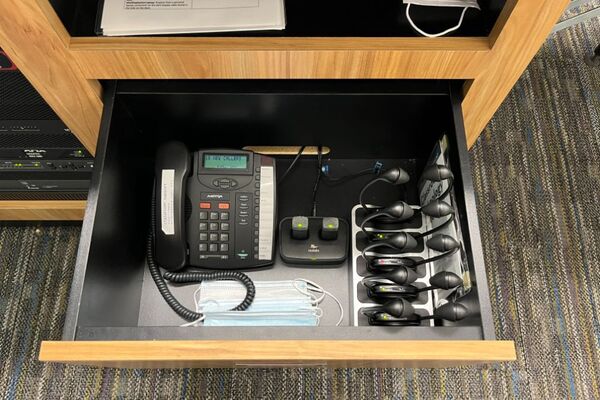 Pedestal - inside view of drawer showing two wireless mics in charging base and telephone