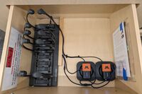 Pedestal - inside view of drawer showing two wireless mics in charging base and assistive listening devices in charger